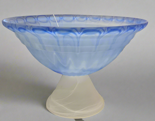 Decorative glass bowl with blue and white design on a reflective surface