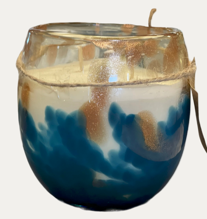 Candle in a glass holder with blue and gold design on a white background
